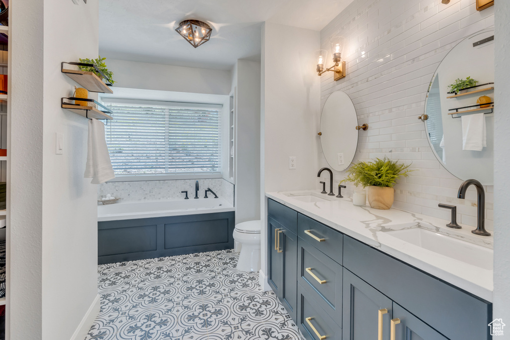 Bathroom featuring a bath, tile floors, toilet, and double sink vanity