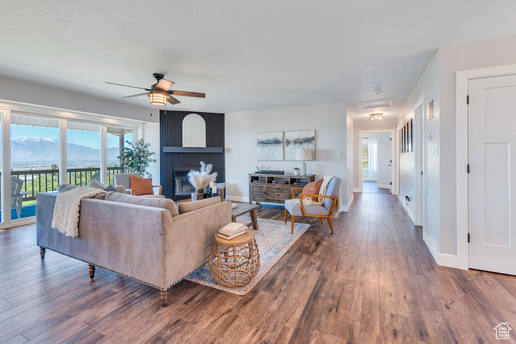 Living room featuring ceiling fan, a mountain view, a fireplace, and dark wood-type flooring