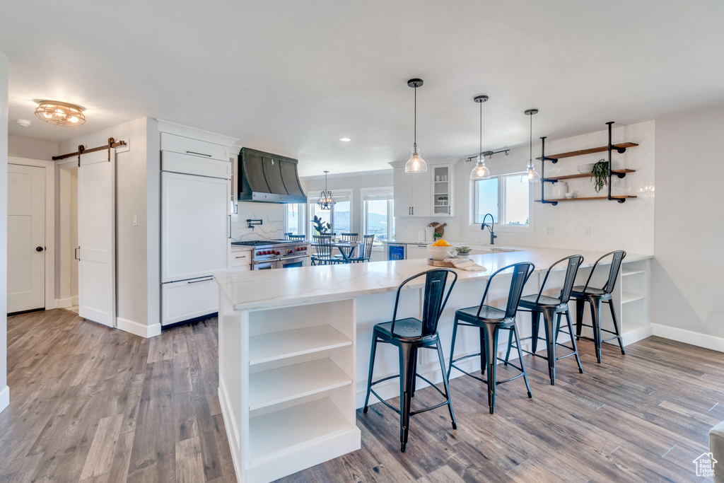 Kitchen with hardwood / wood-style floors, custom range hood, and kitchen peninsula