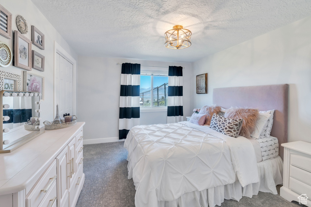 Carpeted bedroom with an inviting chandelier and a textured ceiling