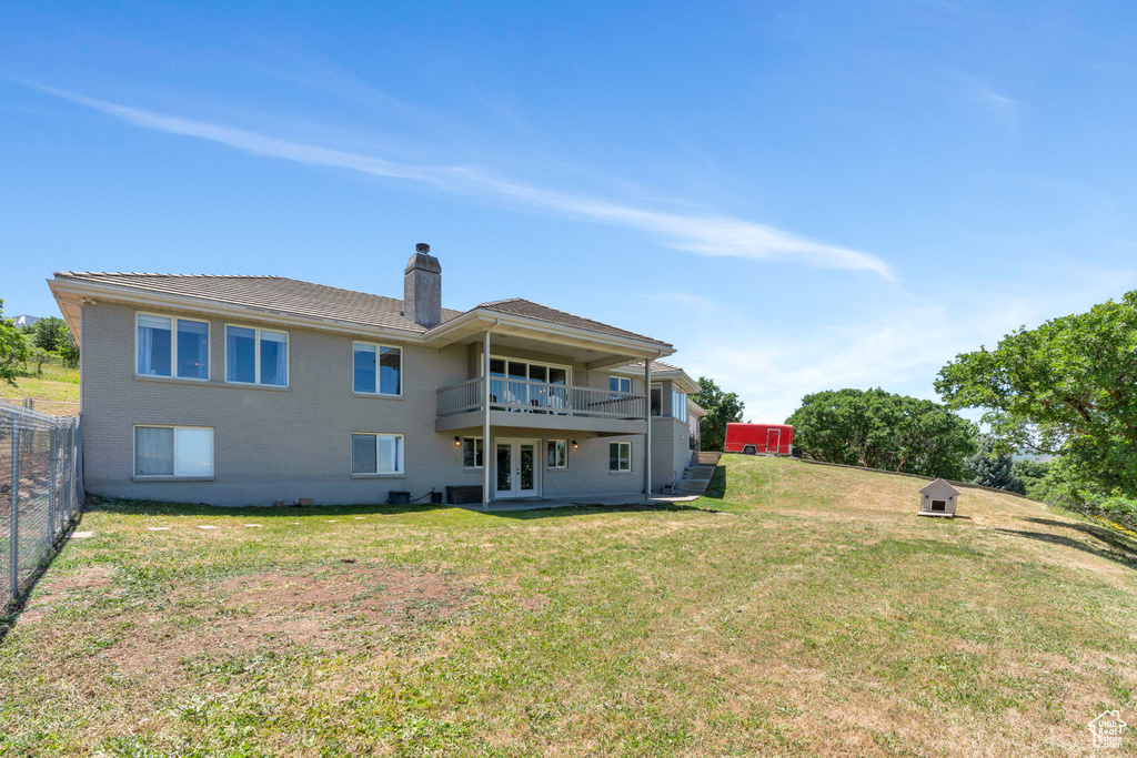 Back of property featuring a yard and a balcony