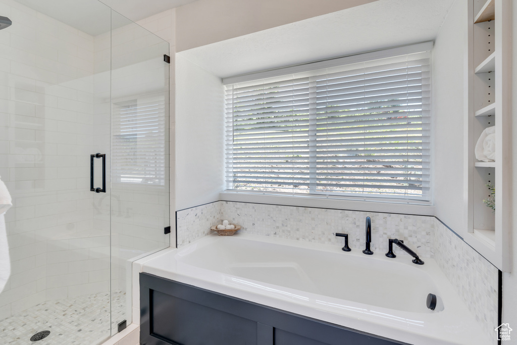 Bathroom featuring built in shelves and separate shower and tub