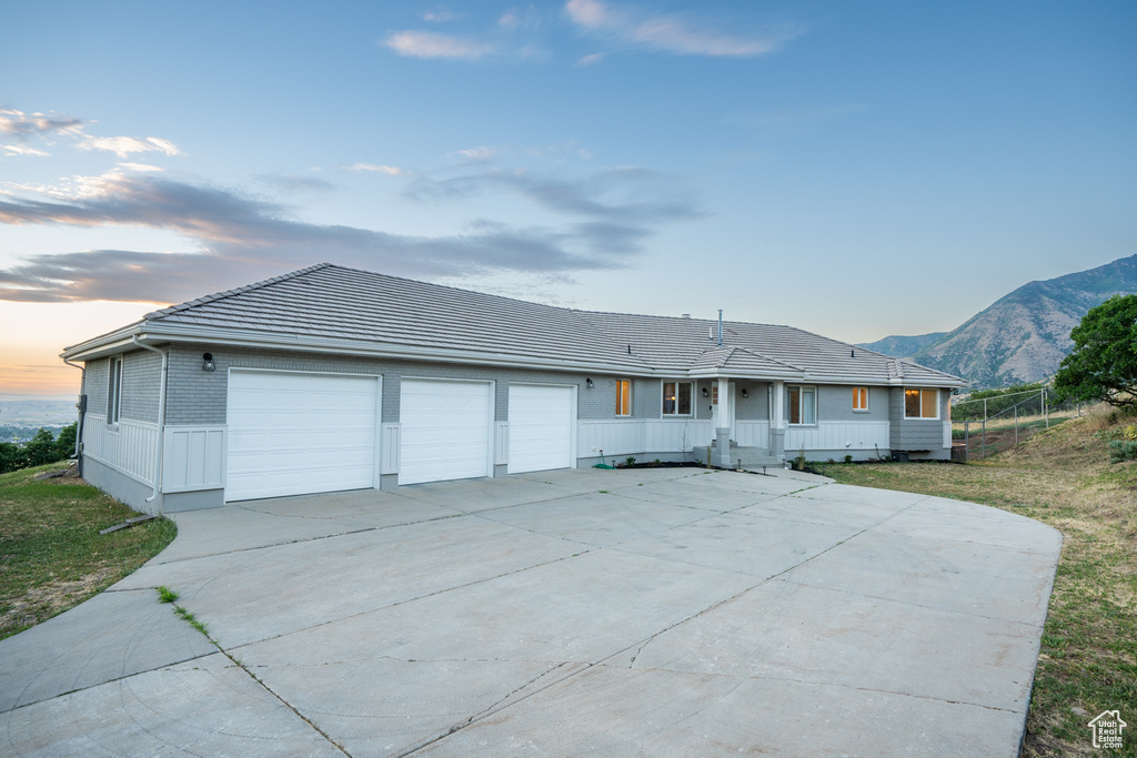 Single story home with a garage, a mountain view, and a lawn