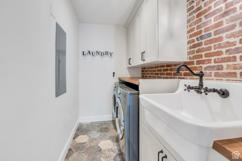 Washroom with separate washer and dryer, brick wall, cabinets, and light tile floors