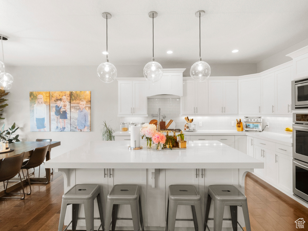 Kitchen featuring white cabinetry, backsplash, and dark hardwood / wood-style floors