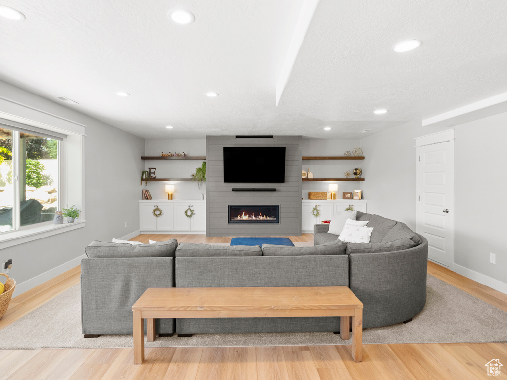 Living room featuring brick wall, a large fireplace, and light hardwood / wood-style flooring