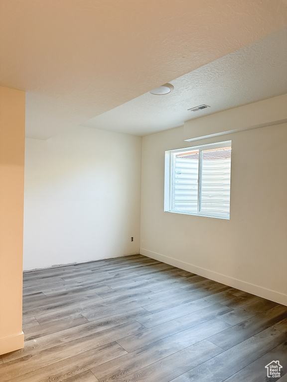 Unfurnished room with a textured ceiling and light wood-type flooring