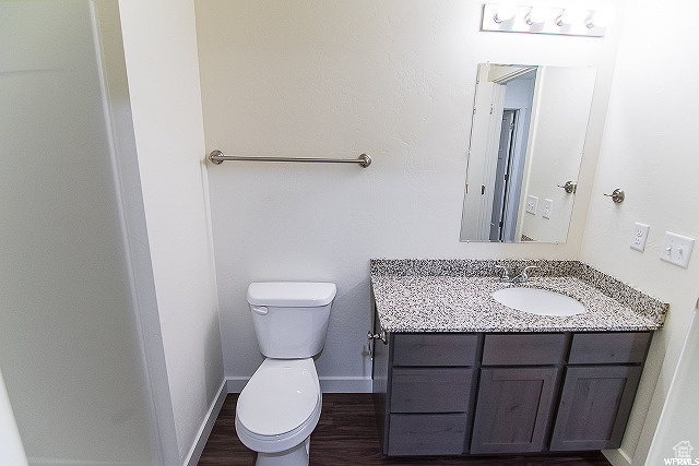 Bathroom featuring wood-type flooring, vanity, and toilet