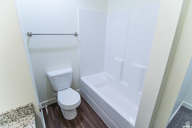 Bathroom featuring hardwood / wood-style floors, toilet, and shower / bathtub combination