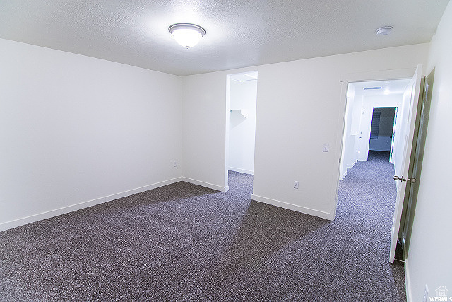 Unfurnished room featuring dark carpet and a textured ceiling