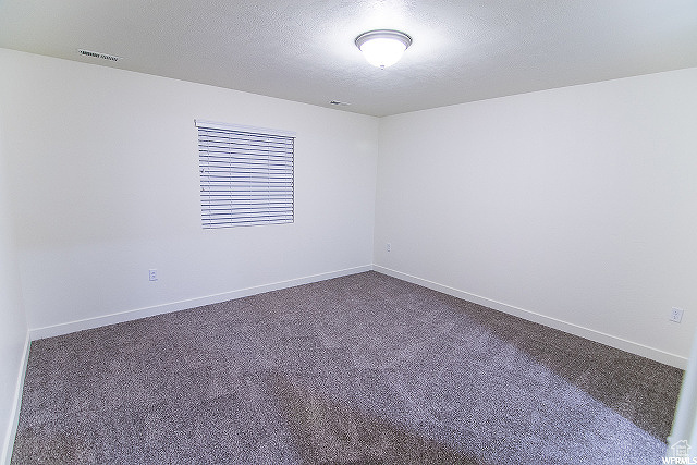 Empty room with carpet flooring and a textured ceiling