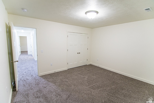 Unfurnished room with a textured ceiling and carpet flooring