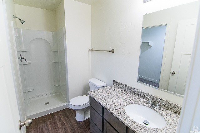 Bathroom with walk in shower, vanity, toilet, and hardwood / wood-style floors