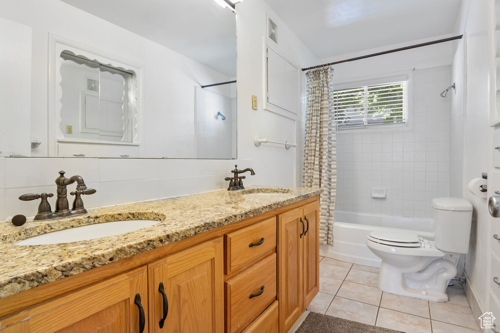 Full bathroom with shower / bathtub combination with curtain, double sink vanity, toilet, and tile floors