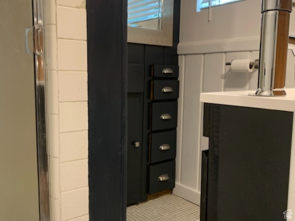 Bathroom with tile flooring, an enclosed shower, and vanity