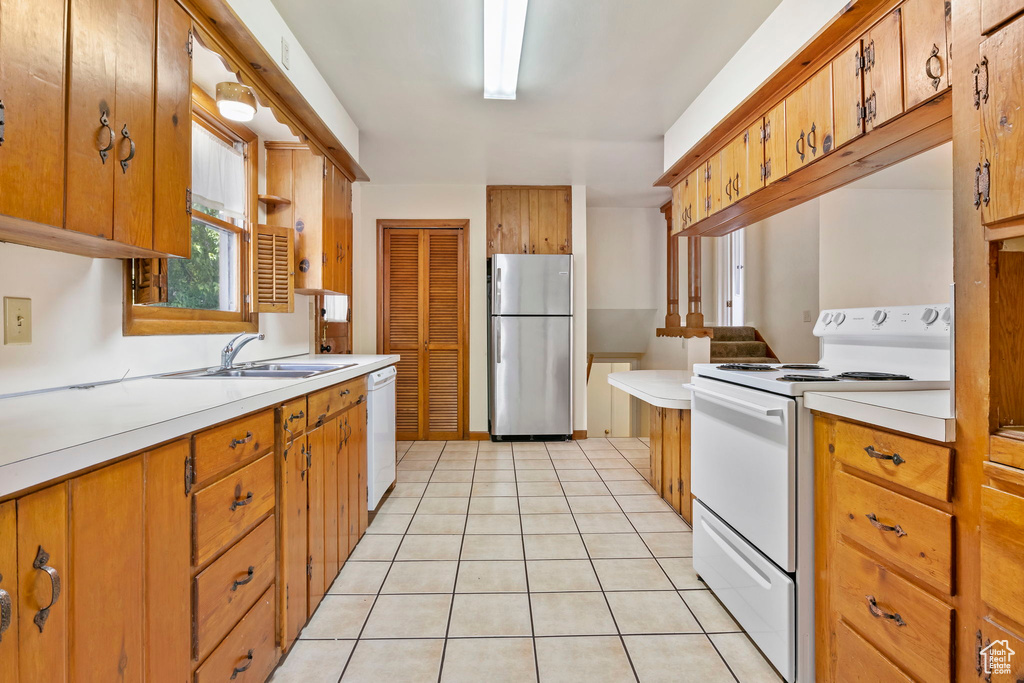 Kitchen with white appliances, sink, and light tile flooring