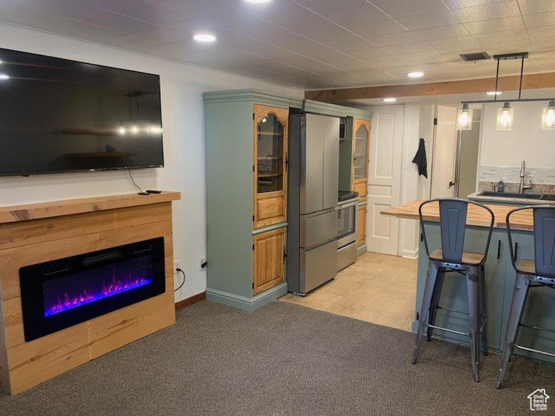 Kitchen featuring a breakfast bar area, blue cabinetry, pendant lighting, sink, and light tile floors