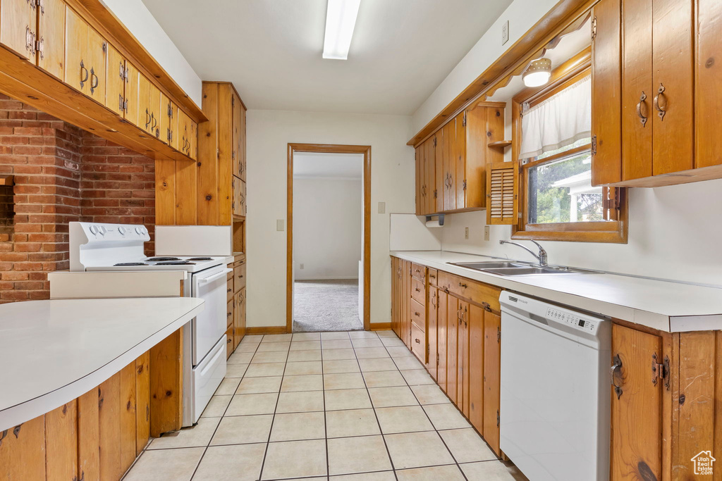 Kitchen with sink, white appliances, and light tile floors