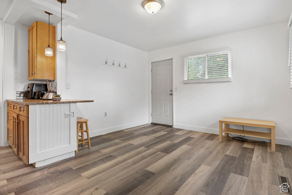 Kitchen with hanging light fixtures, dark wood-type flooring, stone countertops, and a kitchen bar