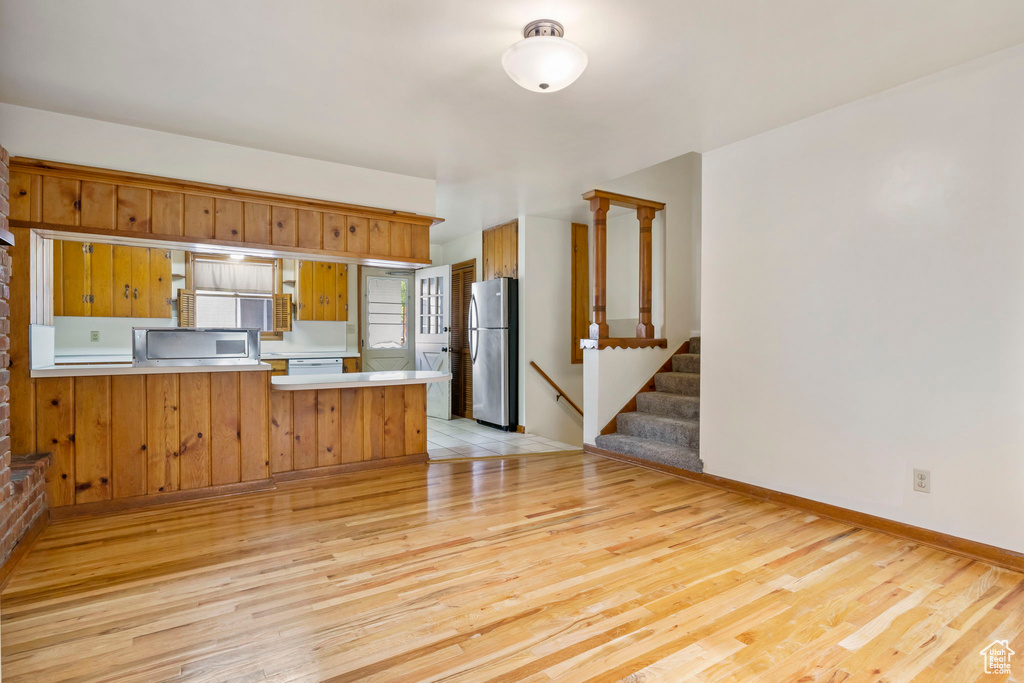 Kitchen with appliances with stainless steel finishes, kitchen peninsula, and light hardwood / wood-style flooring