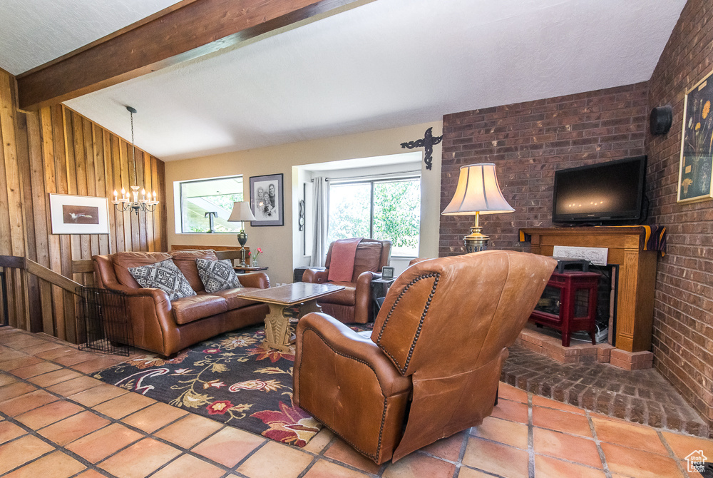 Living room with brick wall, a brick fireplace, tile floors, vaulted ceiling with beams, and wooden walls