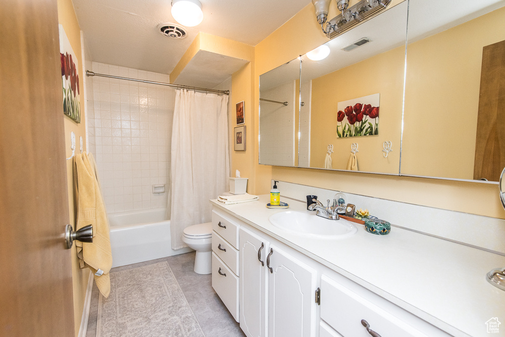 Full bathroom featuring vanity, toilet, tile floors, and shower / tub combo with curtain