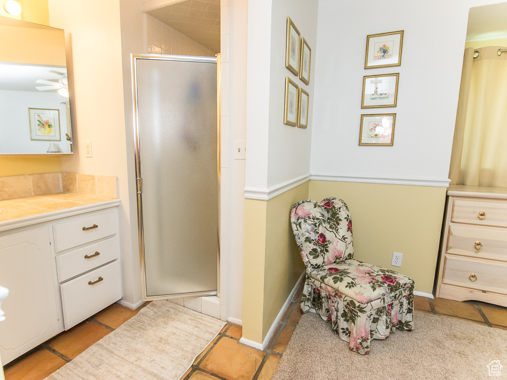 Bathroom with tile floors, walk in shower, vanity, and ceiling fan