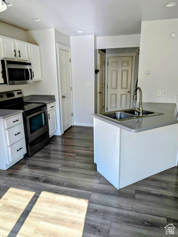 Kitchen featuring appliances with stainless steel finishes, white cabinetry, kitchen peninsula, and sink