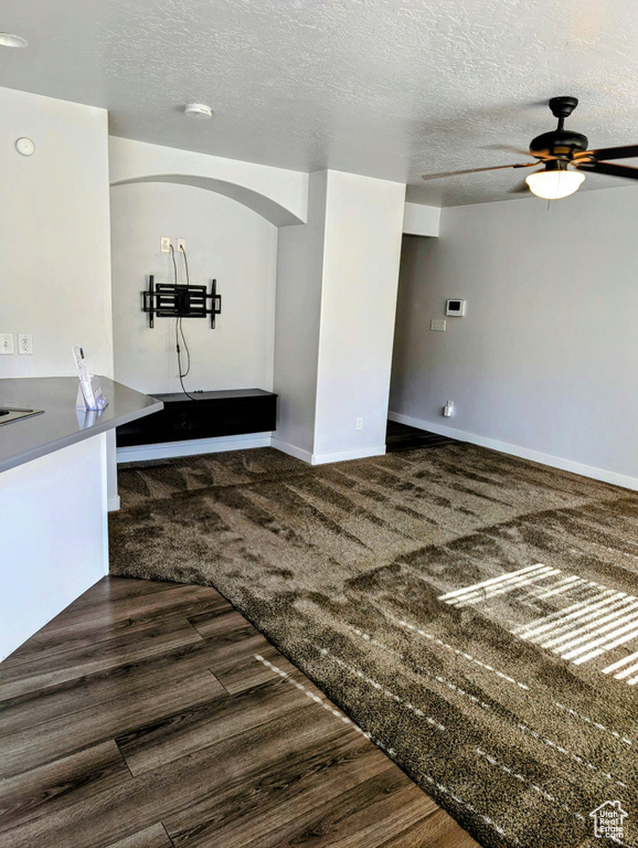 Interior space with dark hardwood / wood-style flooring, ceiling fan, and a textured ceiling