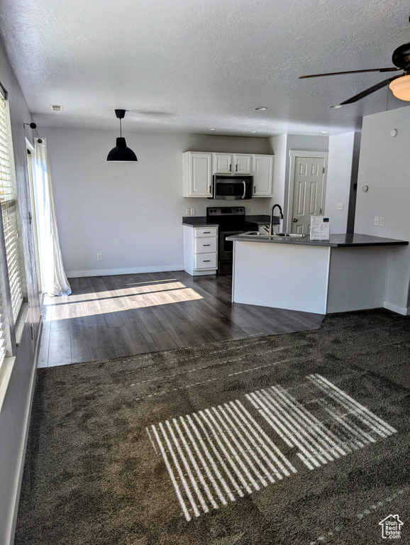 Unfurnished living room featuring dark hardwood / wood-style flooring, sink, ceiling fan, and a textured ceiling