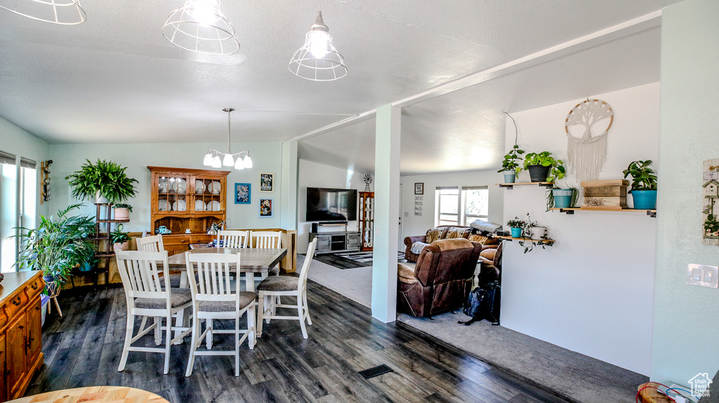 Dining area with a notable chandelier, lofted ceiling, and dark hardwood / wood-style flooring