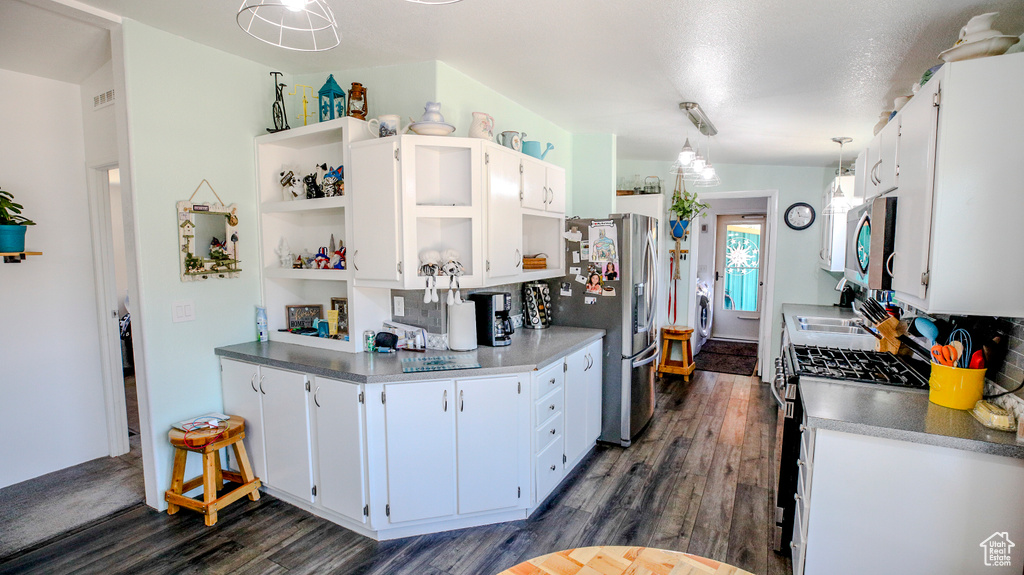 Kitchen with dark hardwood / wood-style floors, decorative light fixtures, white cabinetry, and appliances with stainless steel finishes