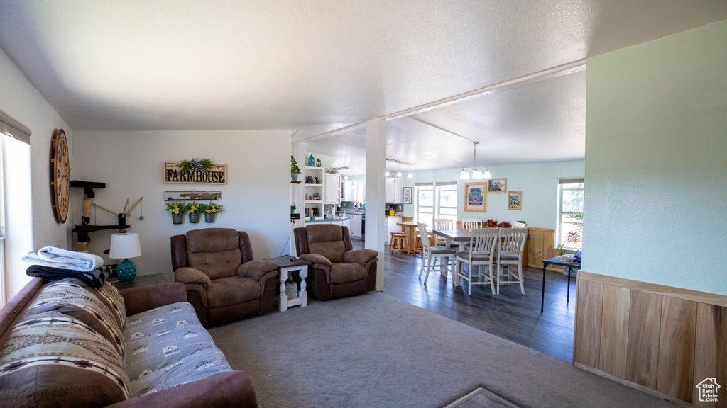 Living room with a chandelier, dark wood-type flooring, and vaulted ceiling