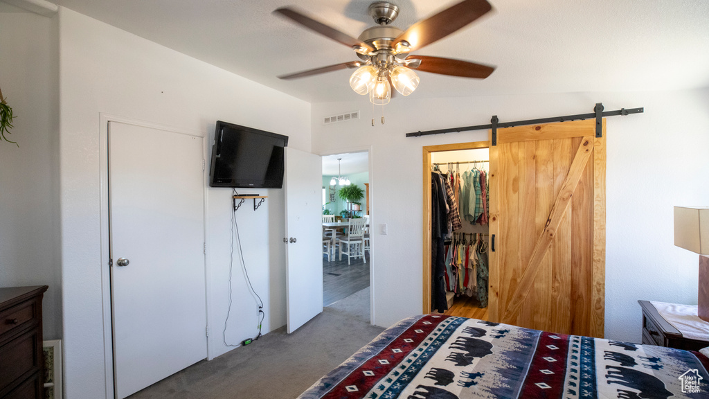 Carpeted bedroom with a barn door, ceiling fan, a closet, and lofted ceiling