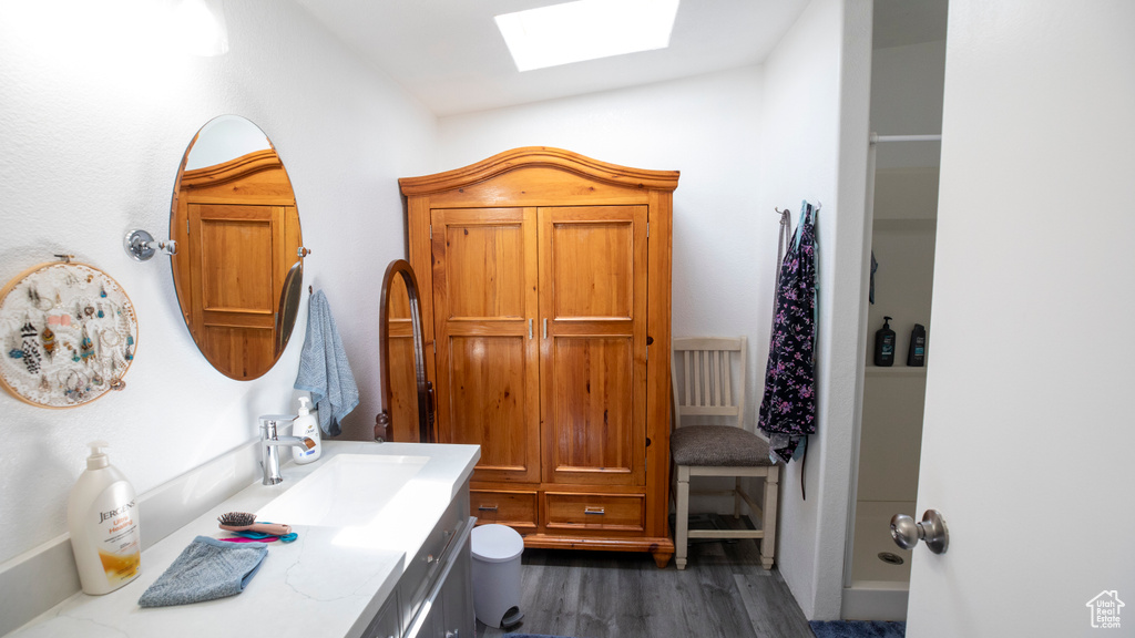 Bathroom with wood-type flooring, vanity, and vaulted ceiling with skylight