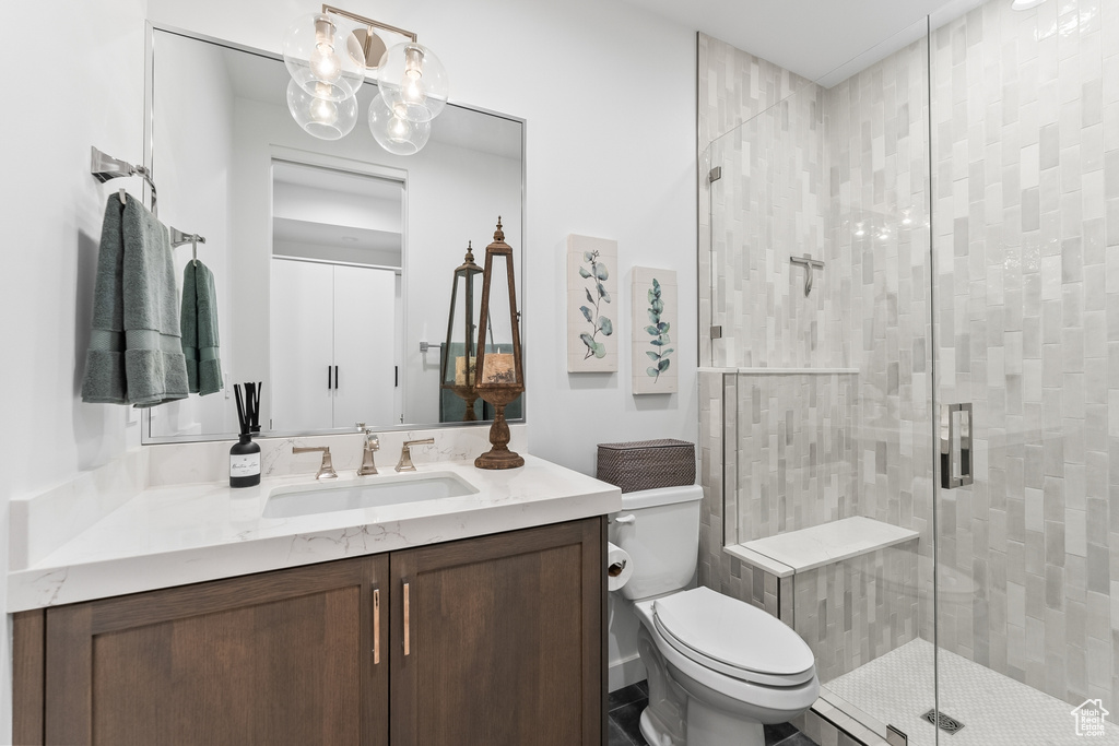 Bathroom featuring vanity, toilet, and a shower with door