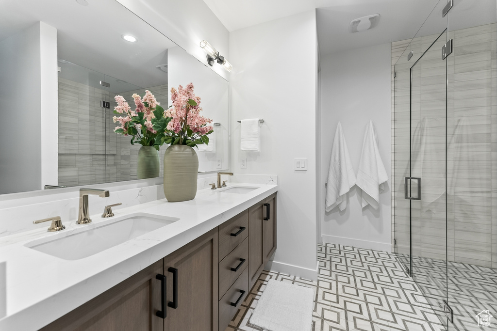 Bathroom featuring tile floors, a shower with shower door, large vanity, and double sink