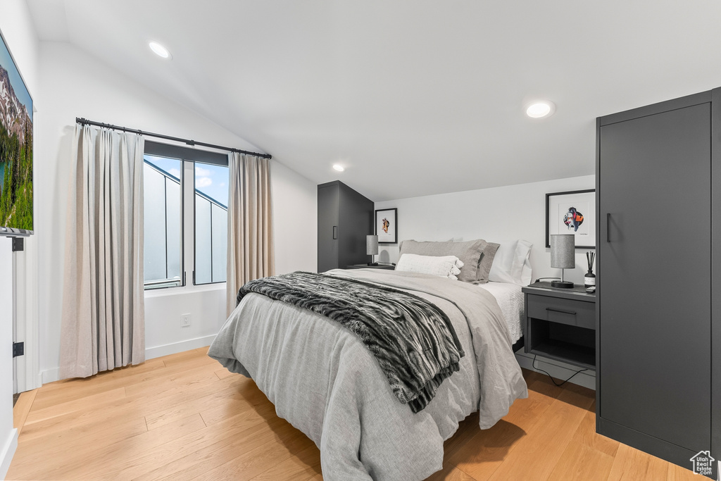 Bedroom with light hardwood / wood-style floors and lofted ceiling