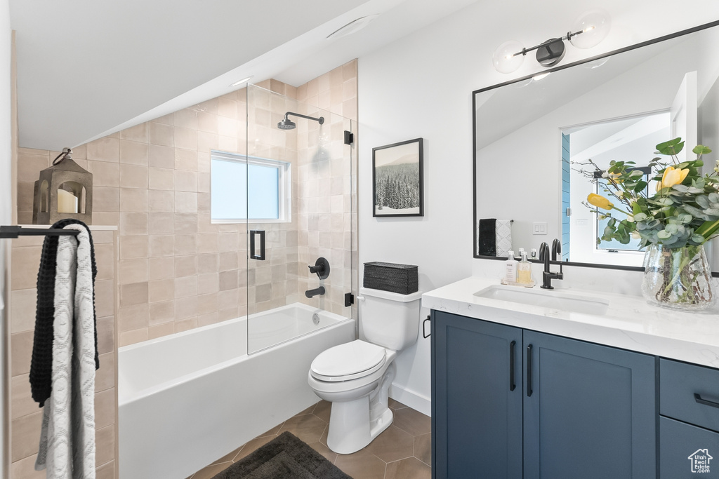 Full bathroom with lofted ceiling, tile floors, enclosed tub / shower combo, large vanity, and toilet