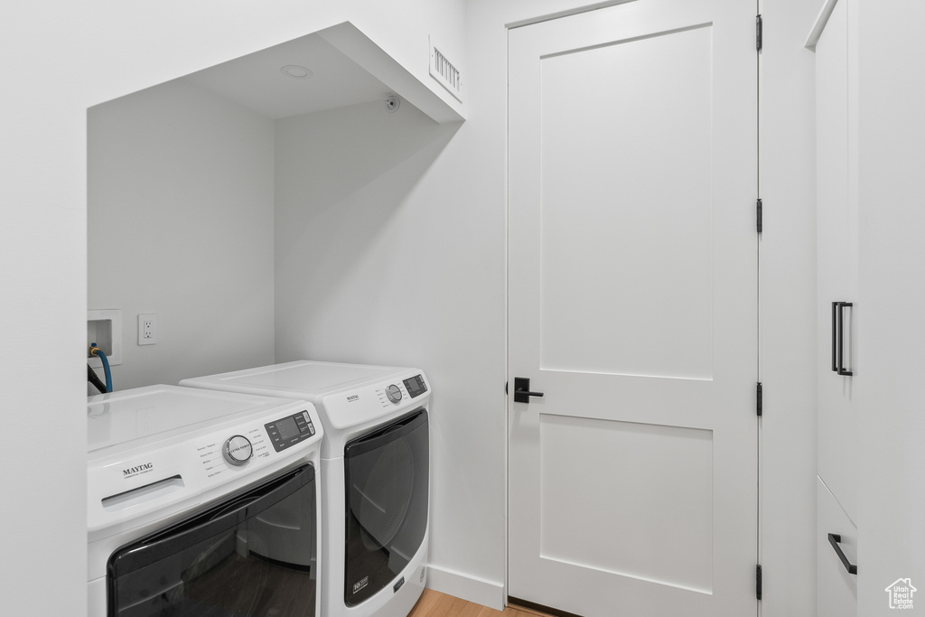 Laundry room with hookup for a washing machine, washer and dryer, and light hardwood / wood-style flooring