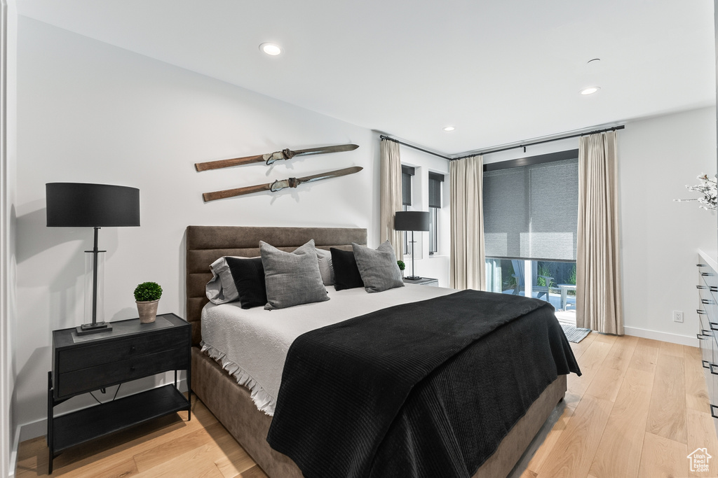 Bedroom with expansive windows, light hardwood / wood-style floors, and access to exterior