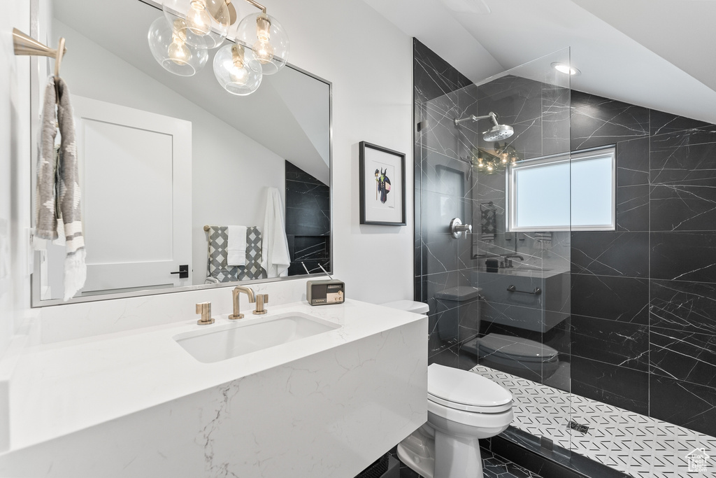 Bathroom featuring vaulted ceiling, oversized vanity, toilet, a tile shower, and tile flooring