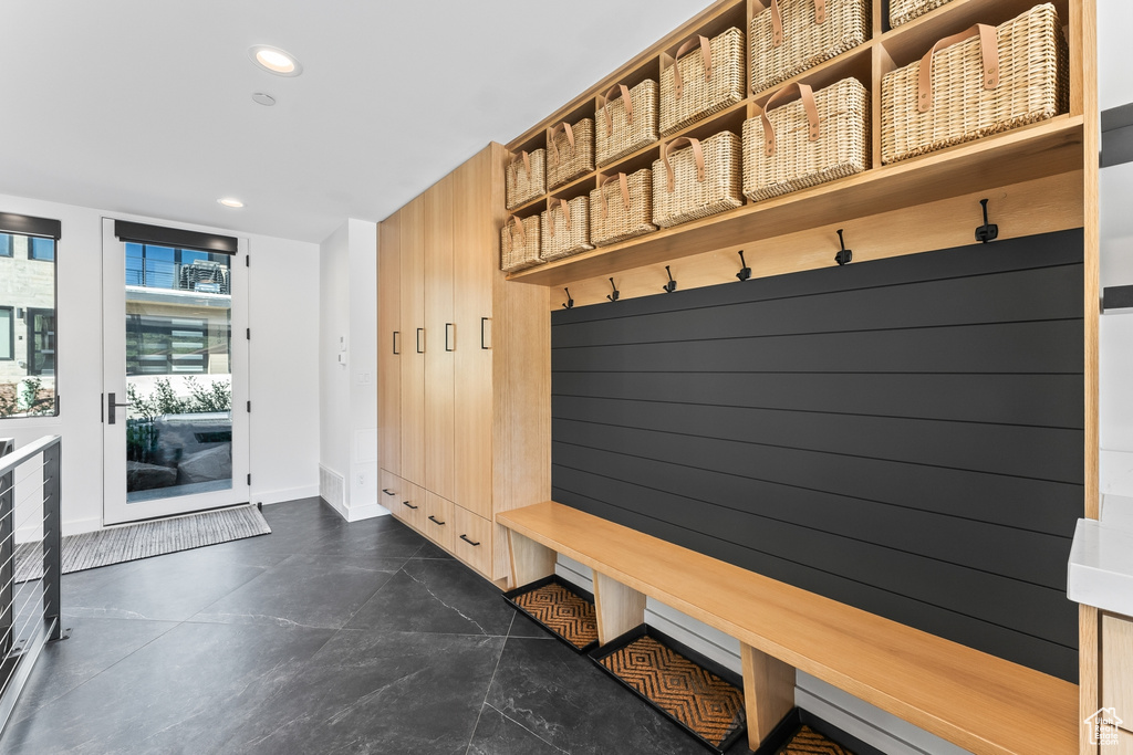 Mudroom with dark tile flooring and wood walls