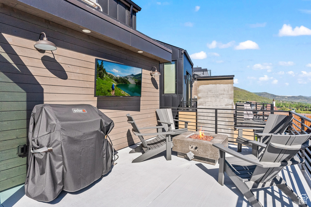 Wooden terrace with an outdoor fire pit, a mountain view, and grilling area