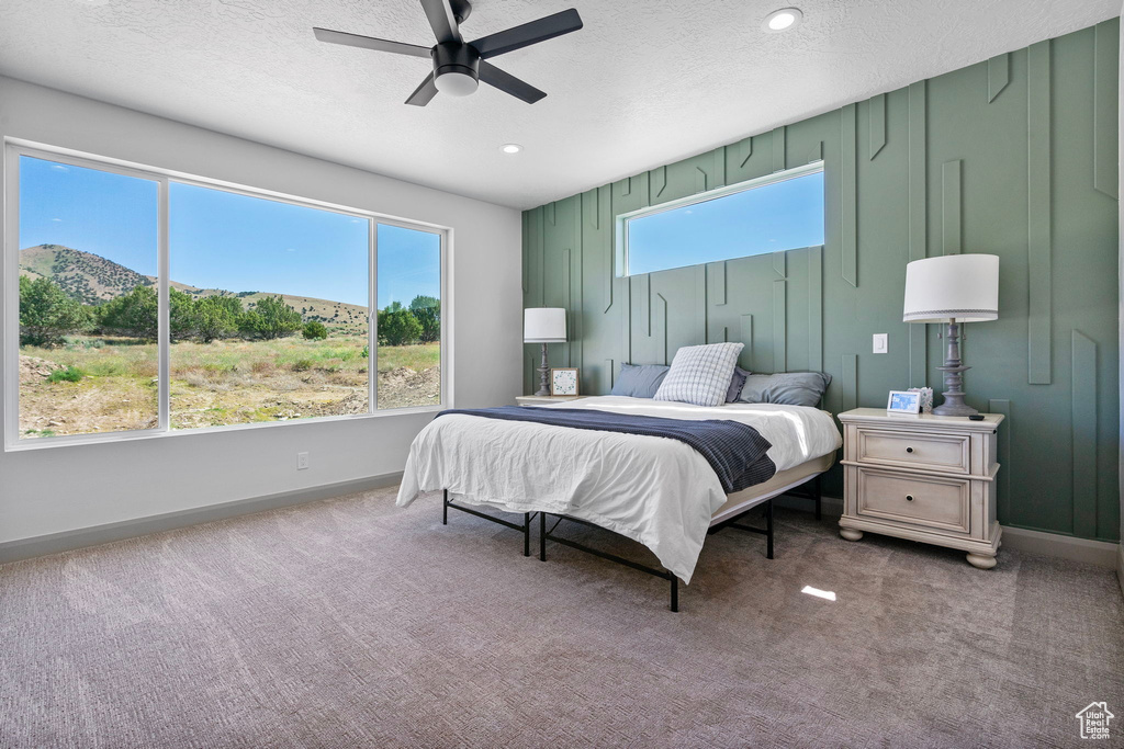 Carpeted bedroom featuring ceiling fan and a textured ceiling