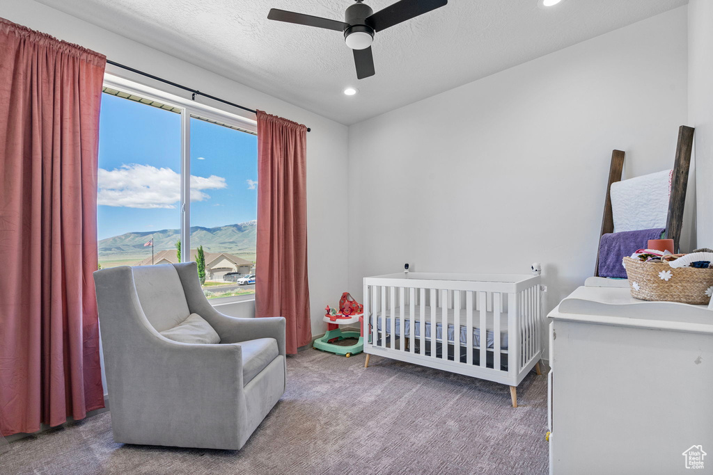 Bedroom with a nursery area, ceiling fan, and carpet floors