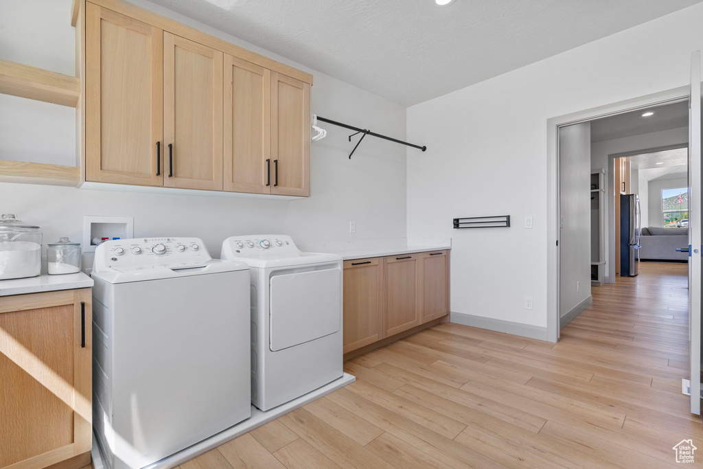 Laundry room featuring washer and dryer, cabinets, washer hookup, and light hardwood / wood-style flooring