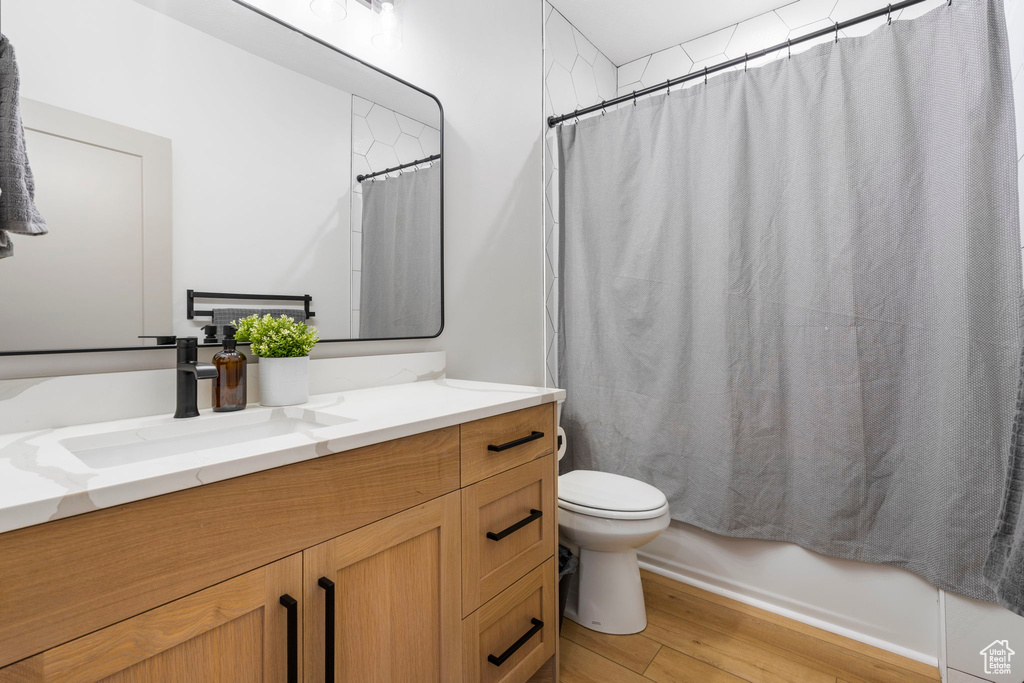 Full bathroom featuring shower / bath combo, hardwood / wood-style flooring, toilet, and vanity