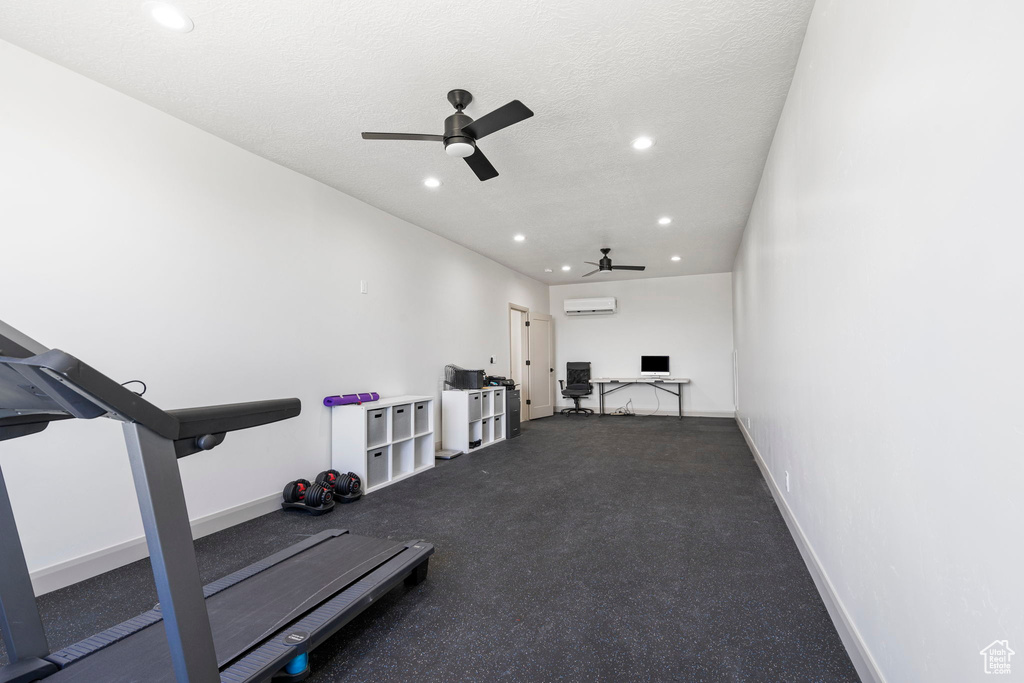 Exercise area featuring ceiling fan, a textured ceiling, and a wall mounted air conditioner