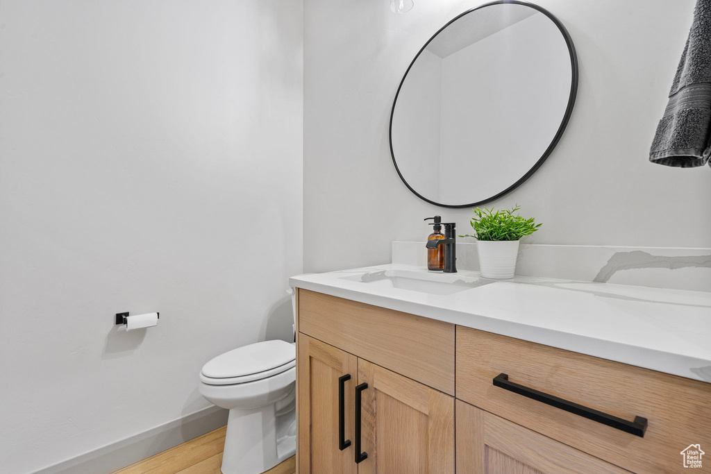 Bathroom featuring wood-type flooring, toilet, and vanity